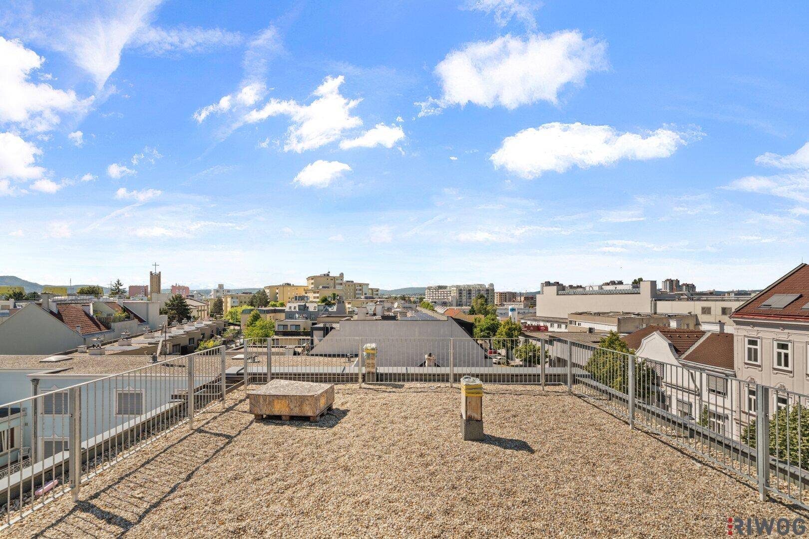 Weitläufige Dachfläche mit Kiesbelag und Panoramablick über die Stadt.