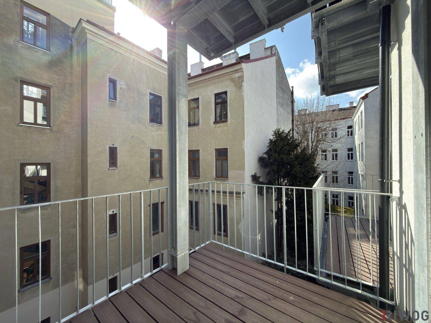 Sonniger Balkon mit Blick auf die umliegenden Altbauten und den Innenhof.