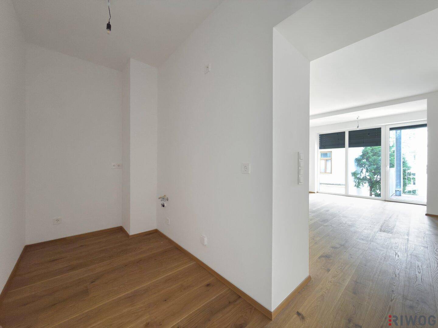 Kleiner Raum mit Parkettboden und Anschlüssen, ideal für eine Kochnische oder Abstellraum.