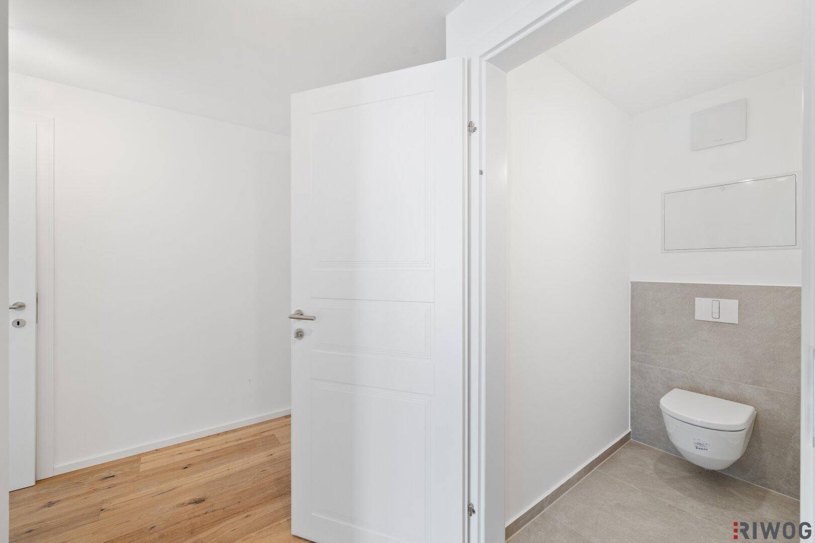 Modernes Gäste-WC mit wandhängender Toilette und stilvollen grauen Fliesen.