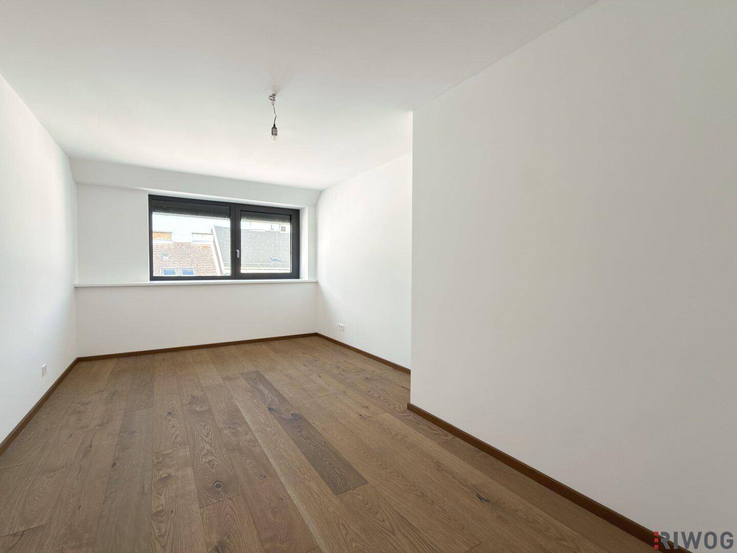 Ruhiges Schlafzimmer mit Holzboden und einem Fenster, das viel Tageslicht hereinlässt.