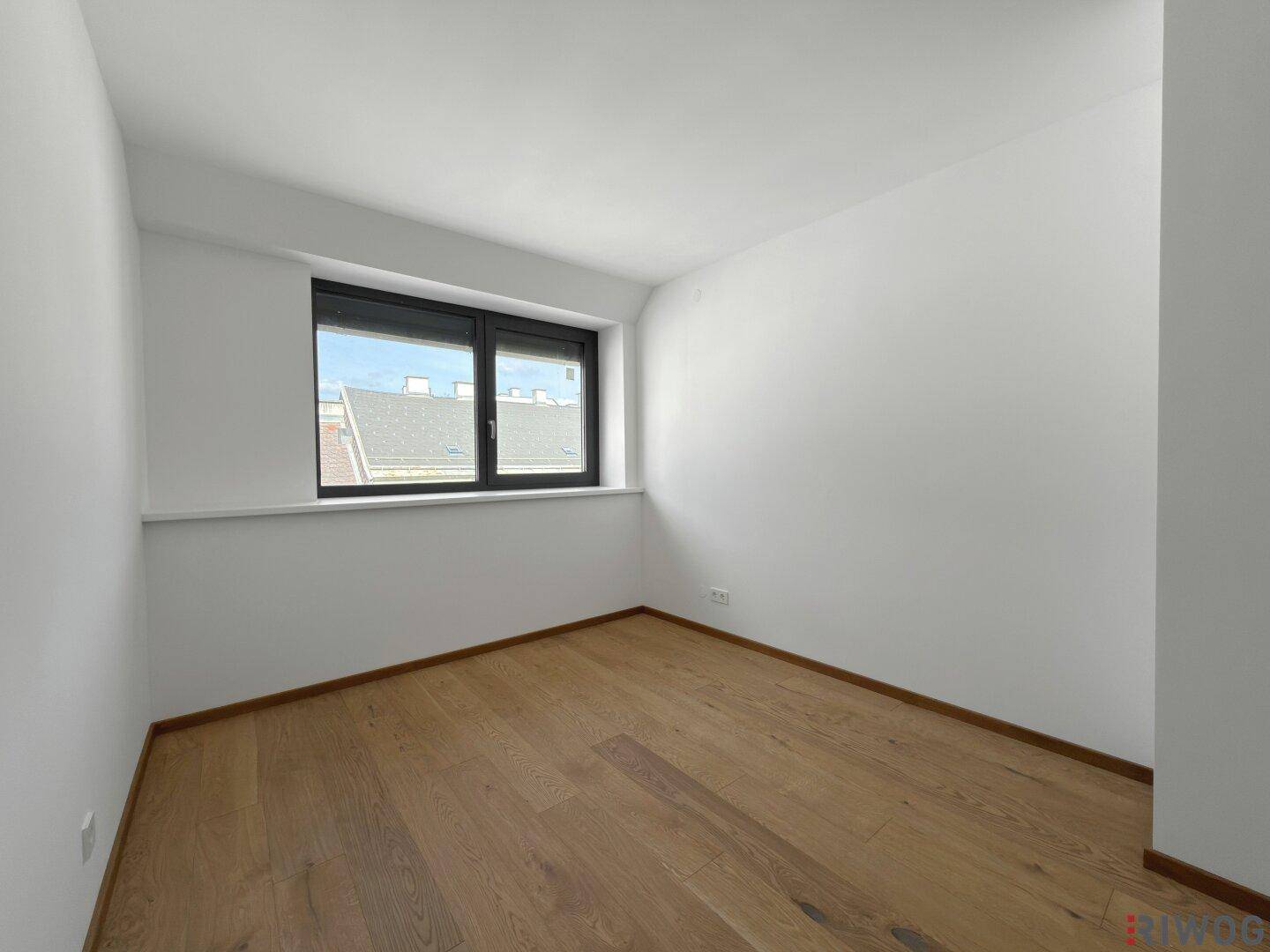 Gemütliches Schlafzimmer mit Holzboden und einem Fenster, das eine angenehme Atmosphäre schafft.
