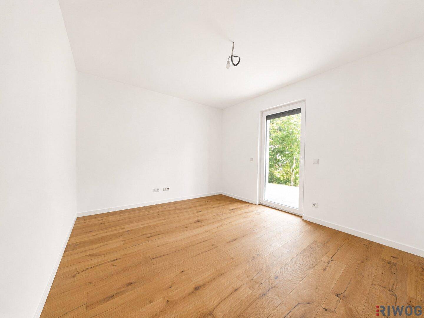 Geräumiges Schlafzimmer mit Holzboden und Zugang zu einem möglichen Balkon oder einer Terrasse.