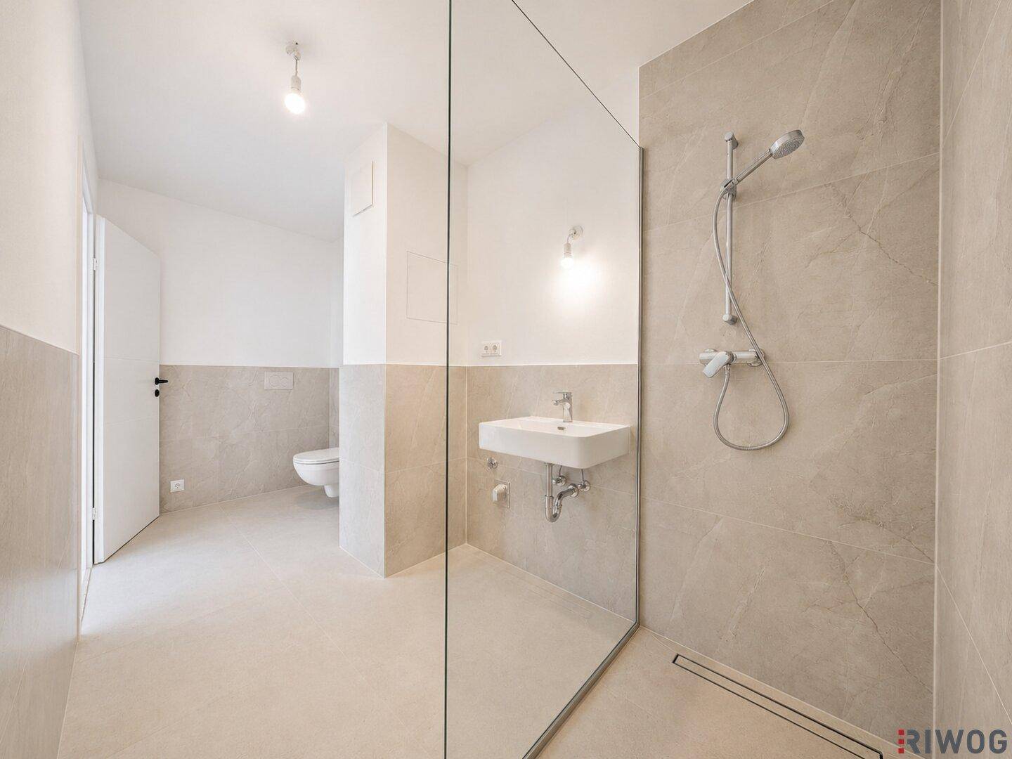Modernes Badezimmer mit begehbarer Dusche, eleganten Fliesen und einem schwebenden Waschbecken sowie Wand-WC.