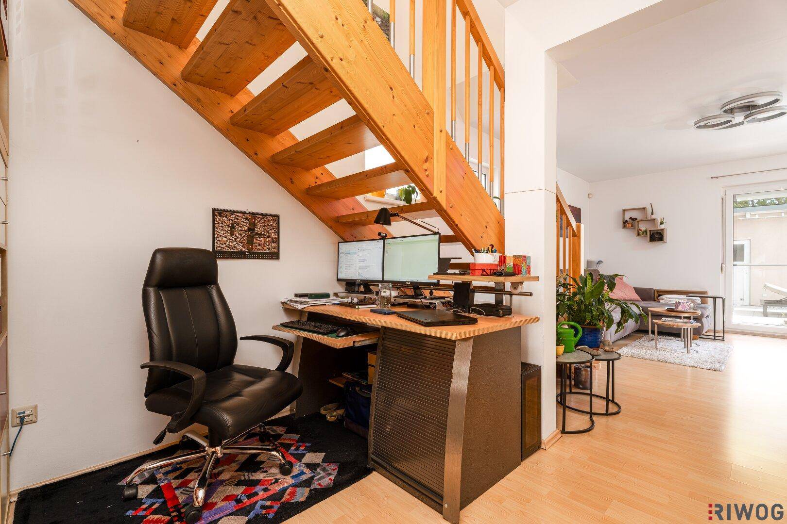 Heller Flur mit Holztreppe und integriertem Arbeitsplatz unter der Treppe.