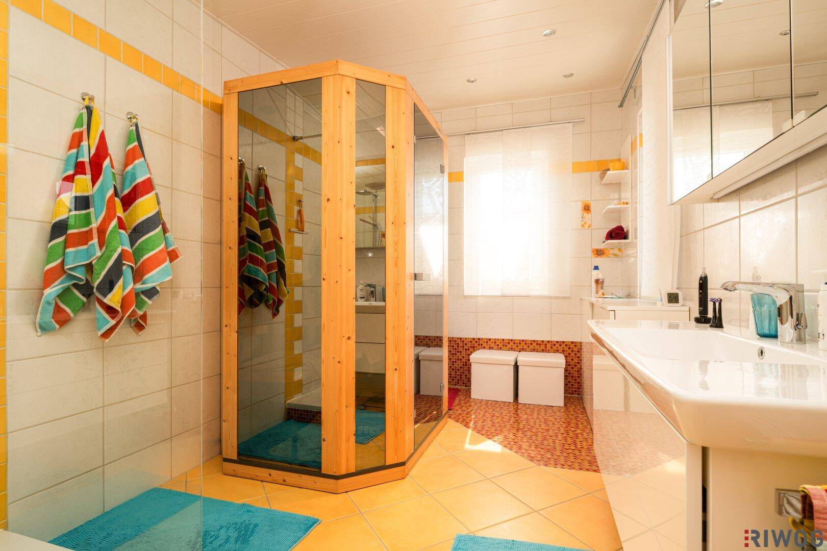 Geräumiges Badezimmer mit Duschkabine, Sauna und gelben Fliesen.