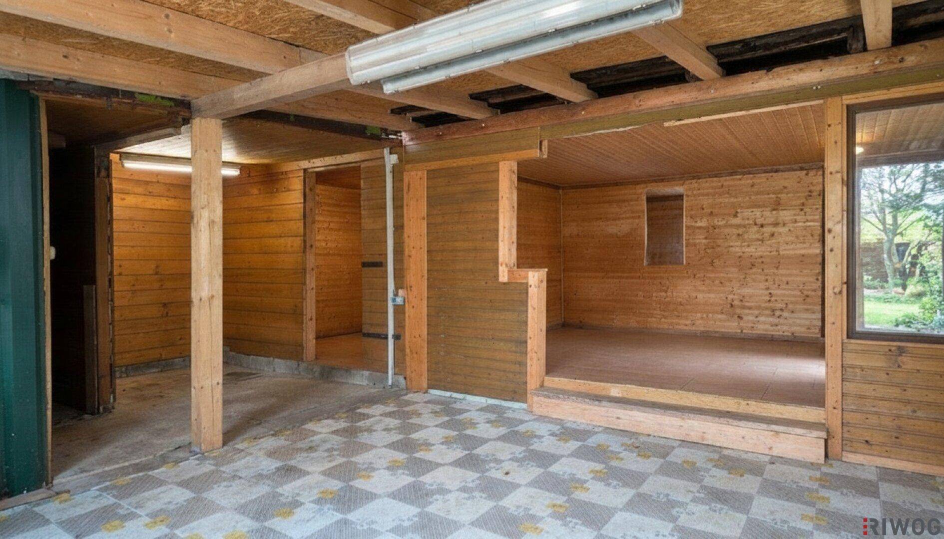 Großer, unfertiger Raum mit sichtbaren Holzbalken und einem karierten Fliesenboden.