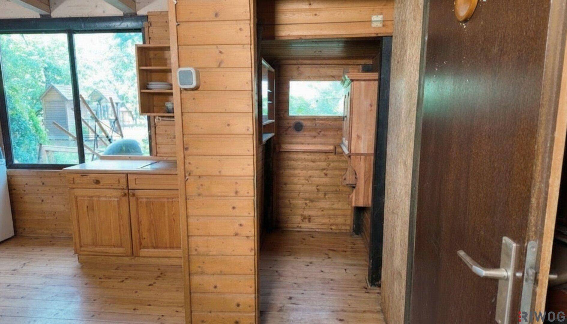 Küchenbereich mit Holzschränken und einem Durchgang zu einem weiteren Raum, alles in Holzoptik.
