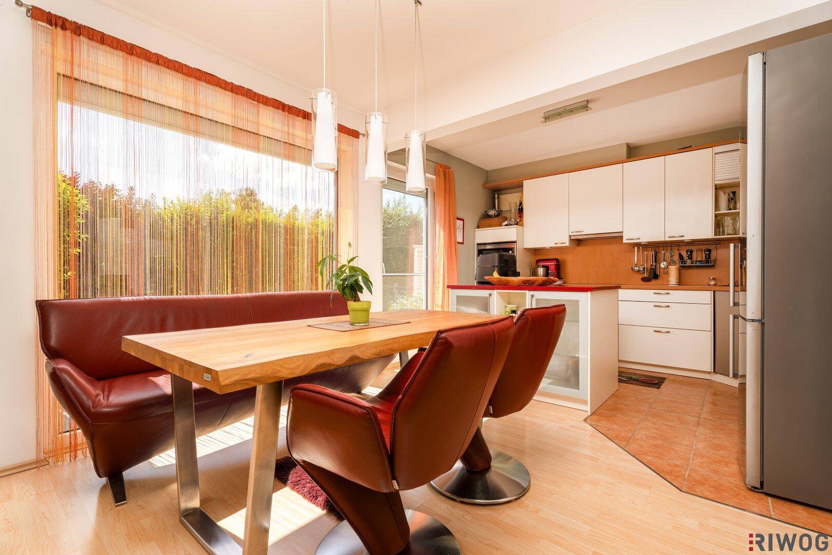 Gemütlicher Essbereich mit Holztisch, Ledersitzbank und Blick in die offene Küche.