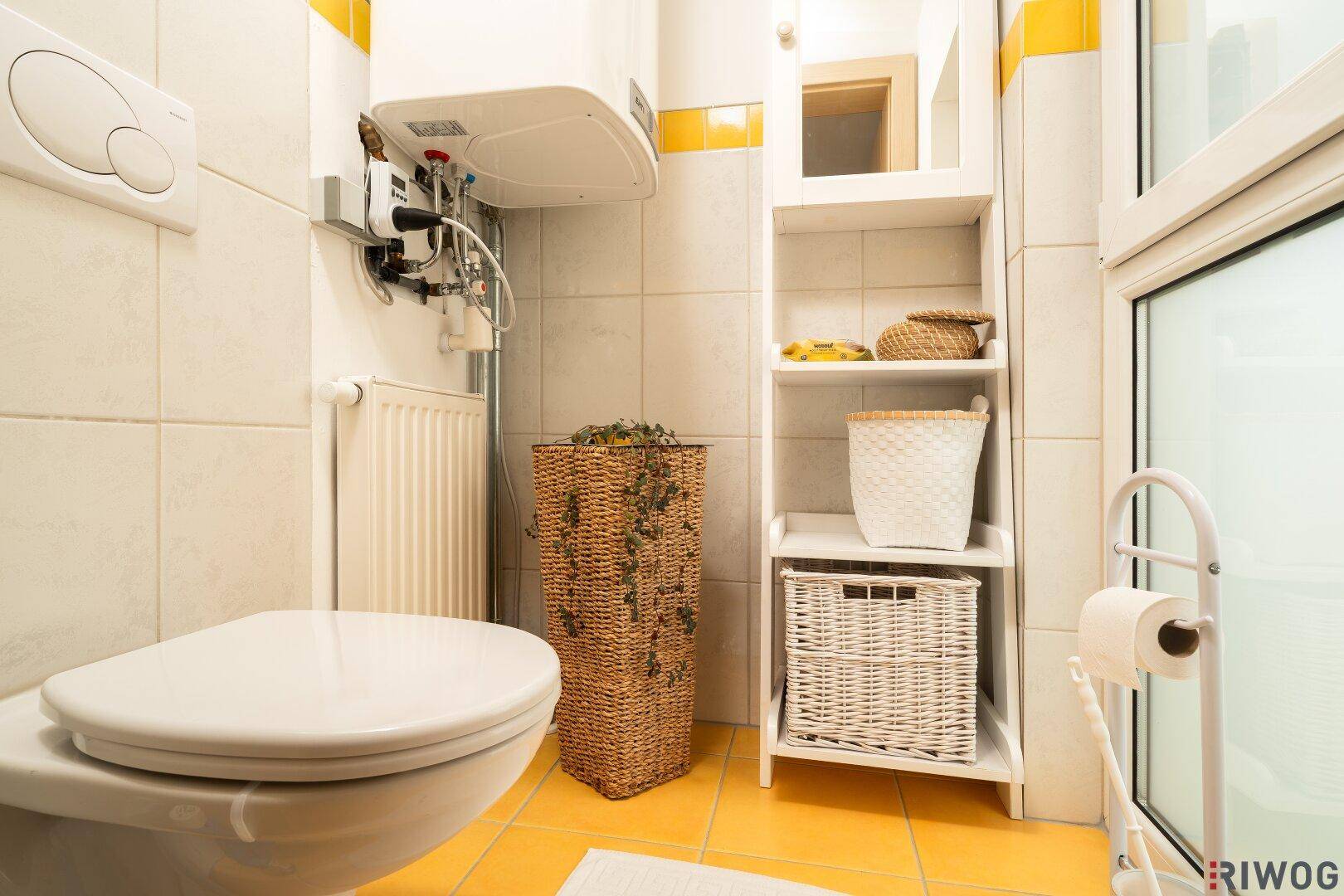 Kleines Gäste-WC mit Toilette, Waschbecken und gelben Bodenfliesen.