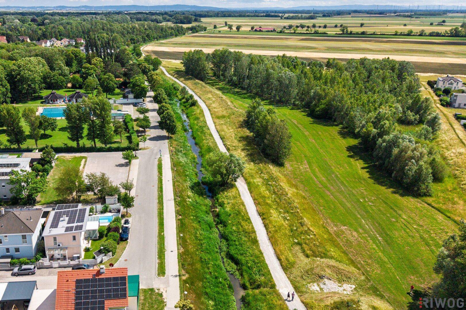 Weitläufige Landschaft mit Feldern, Waldgebieten und einem Flusslauf aus der Vogelperspektive.