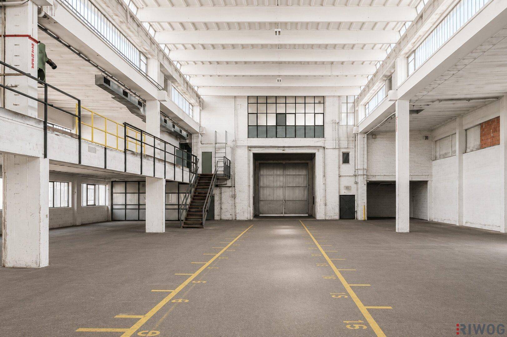 Weitläufige Lagerhalle mit viel Tageslicht, einer großen Laderampe und einer internen Galerie.