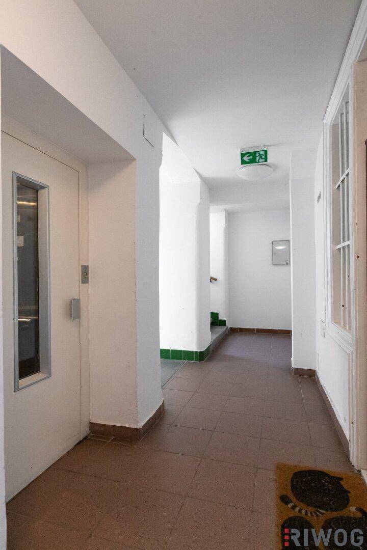 Geräumiger Flur mit Fliesenboden und Zugang zu einem modernen Aufzug, hell und sauber.