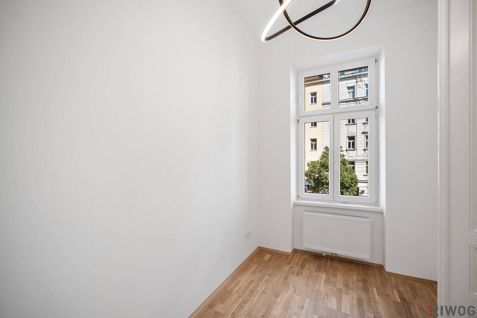 Gemütliches, helles Zimmer mit Parkettboden und einem Fenster, das viel Tageslicht spendet.