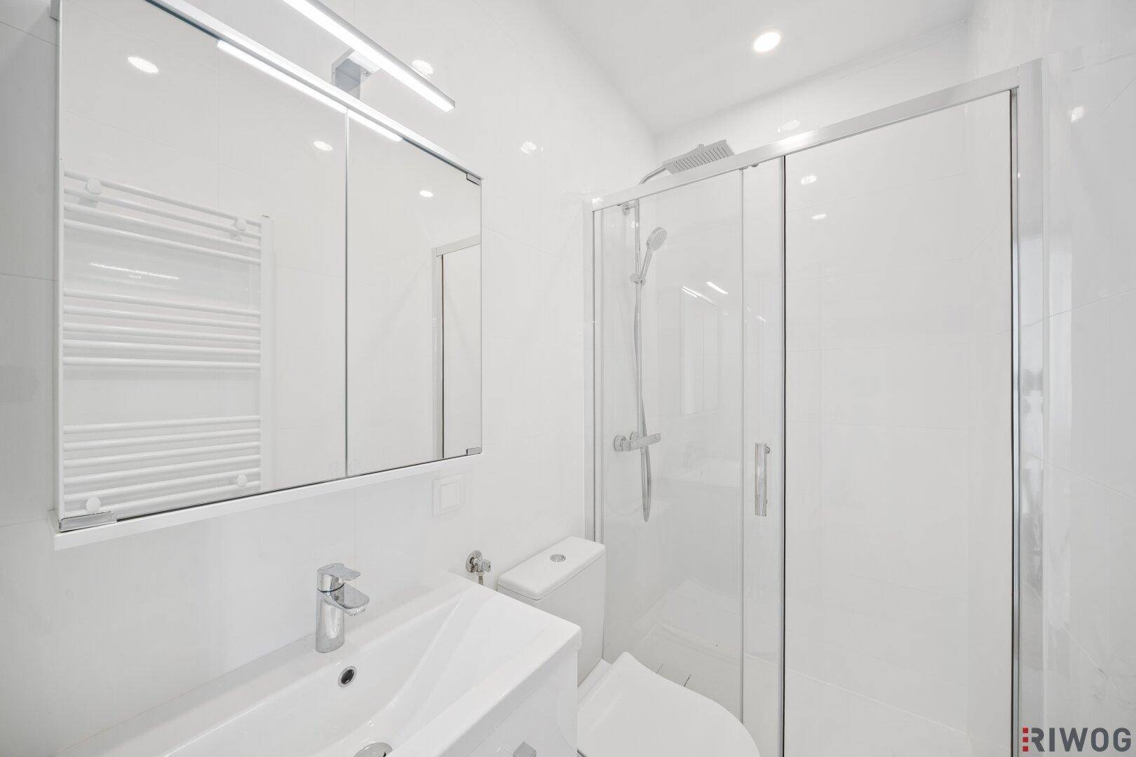 Modernes Badezimmer mit weißer Einrichtung, Dusche und beheiztem Handtuchhalter.