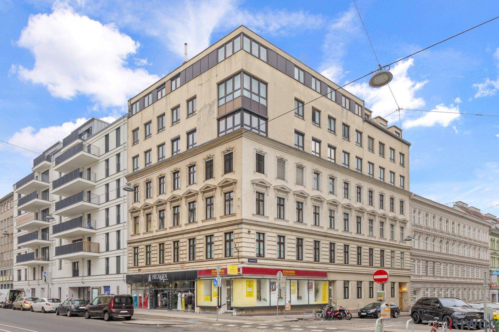 Außenansicht eines Eckgebäudes in der Stadt mit Geschäften im Erdgeschoss.
