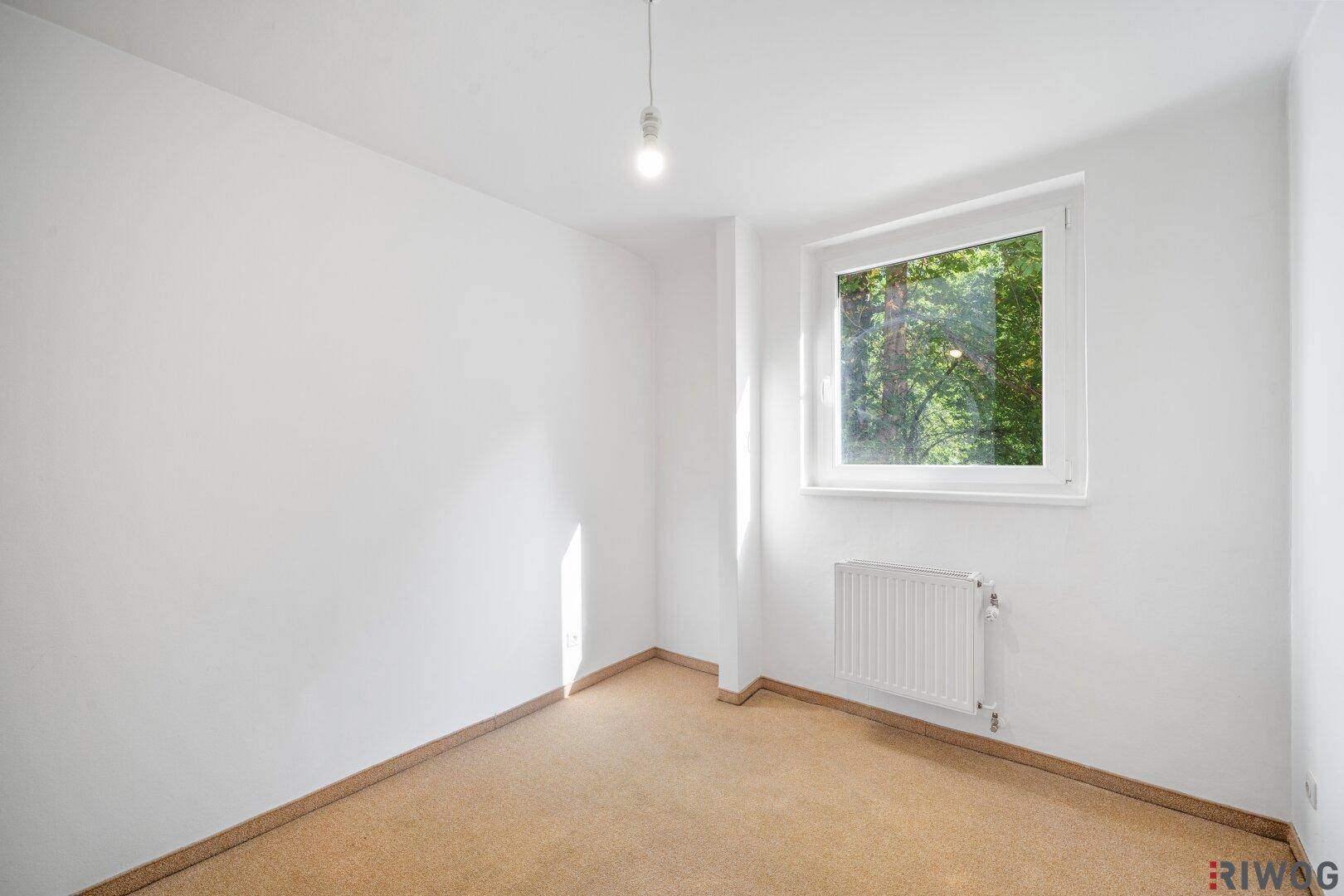 Ruhiges Zimmer mit Korkboden und viel Tageslicht, ideal als Schlaf- oder Arbeitszimmer.