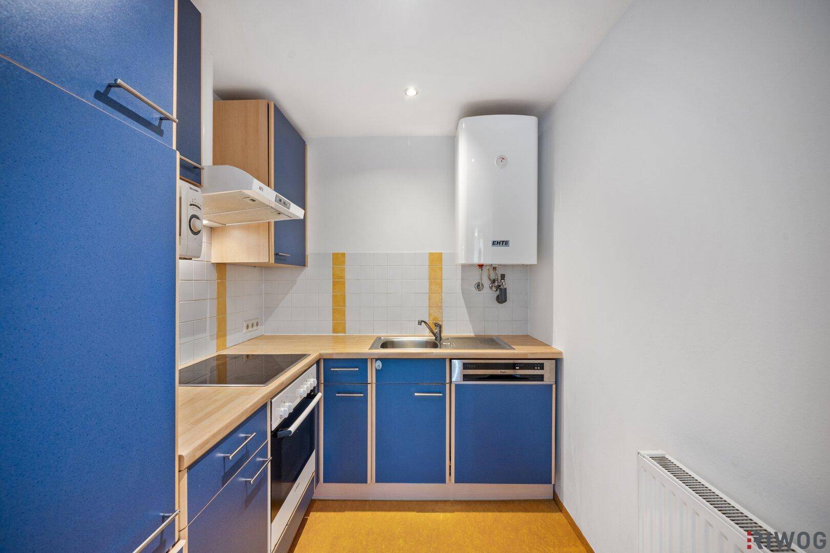 Kompakte Einbauküche in Blau mit Spüle, Kochfeld und Warmwasserboiler.