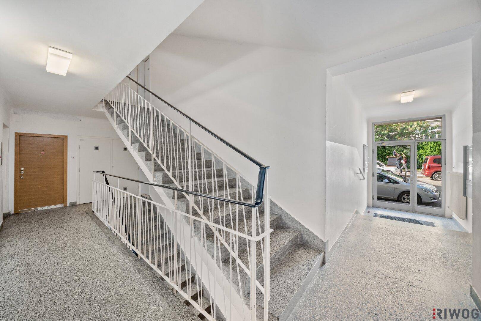 Treppenhaus mit Terrazzoboden und Metallgeländer in einem Mehrfamilienhaus.