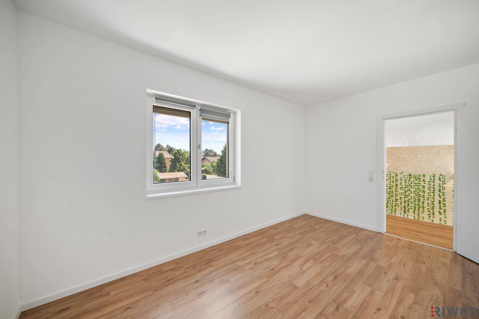 Geräumiges Zimmer mit Holzboden und Fenster, das viel Tageslicht hereinlässt.