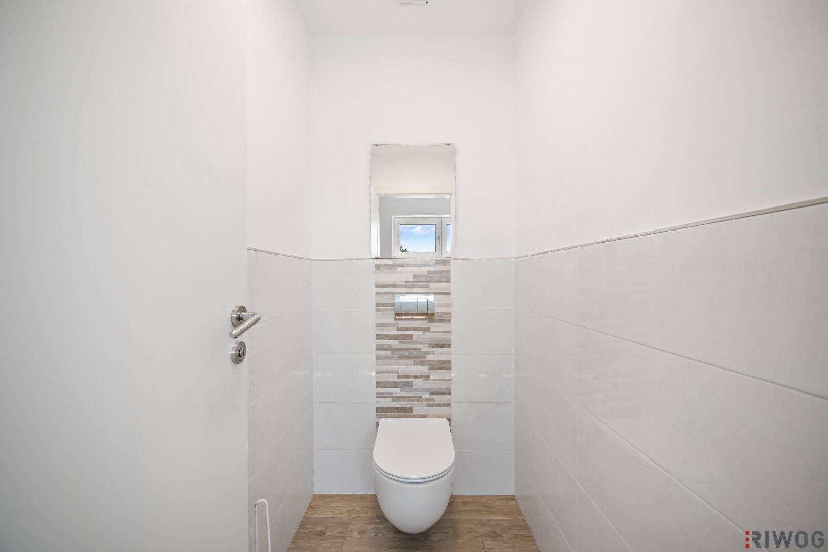 Kleines Gäste-WC mit wandhängender Toilette und modernen Fliesen an den Wänden.