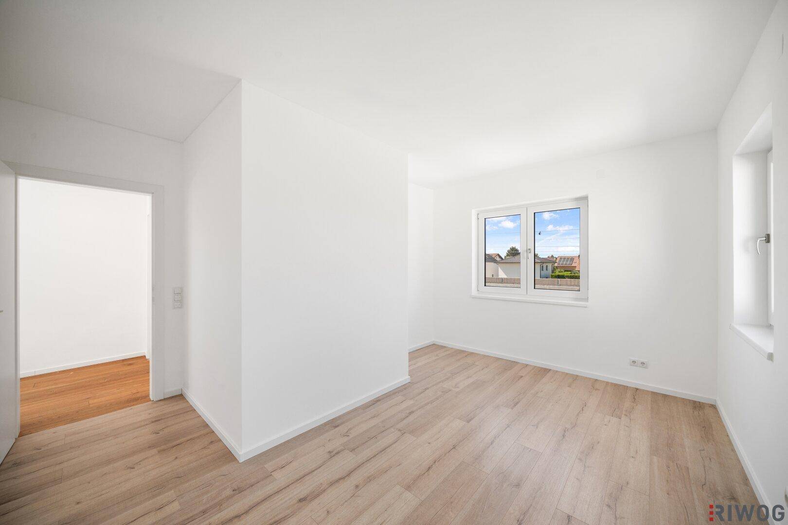 Geräumiges Zimmer mit Holzboden und zwei Fenstern, ideal als Schlaf- oder Arbeitszimmer.