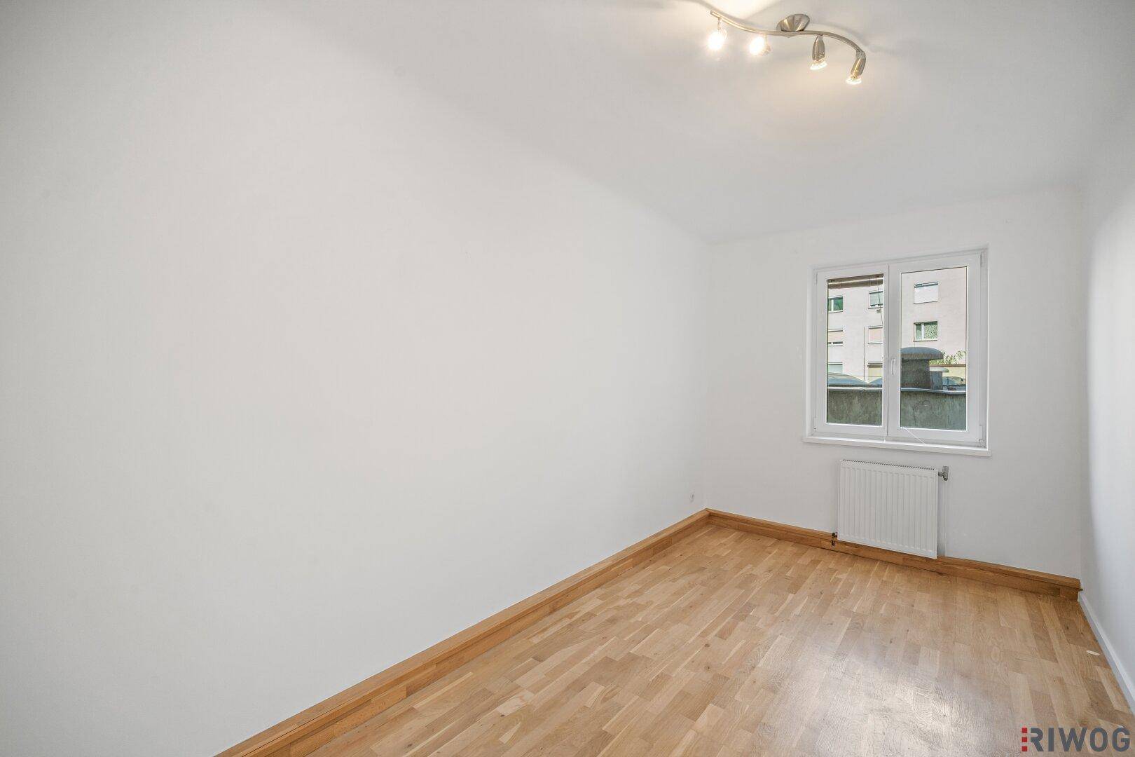 Schlichtes Zimmer mit Parkettboden und weiß gestrichenen Wänden, bereit für neue Bewohner.