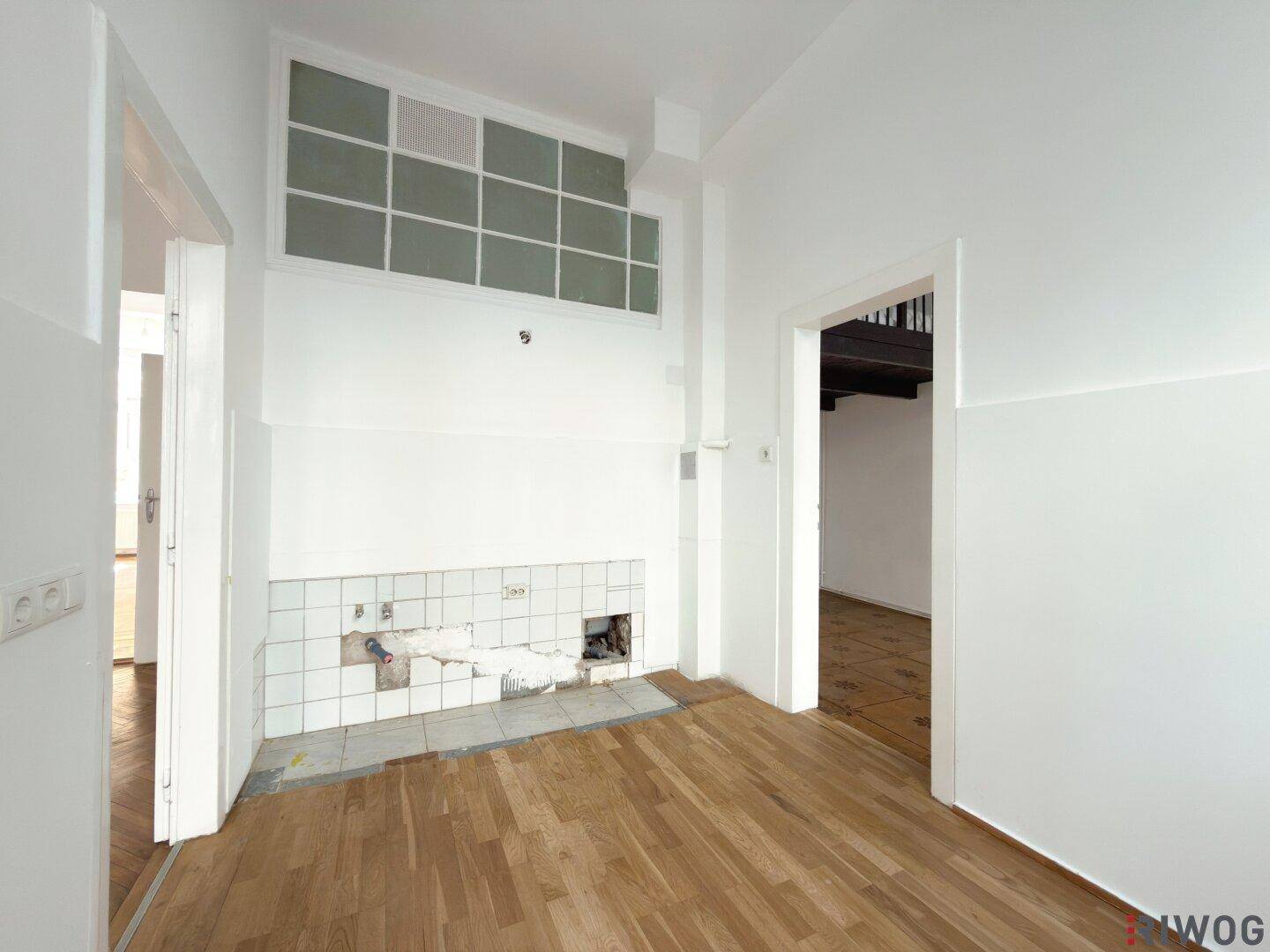 Leerer Küchenbereich mit Fliesenrückwand und Holzfußboden, viel Potenzial zur Gestaltung.