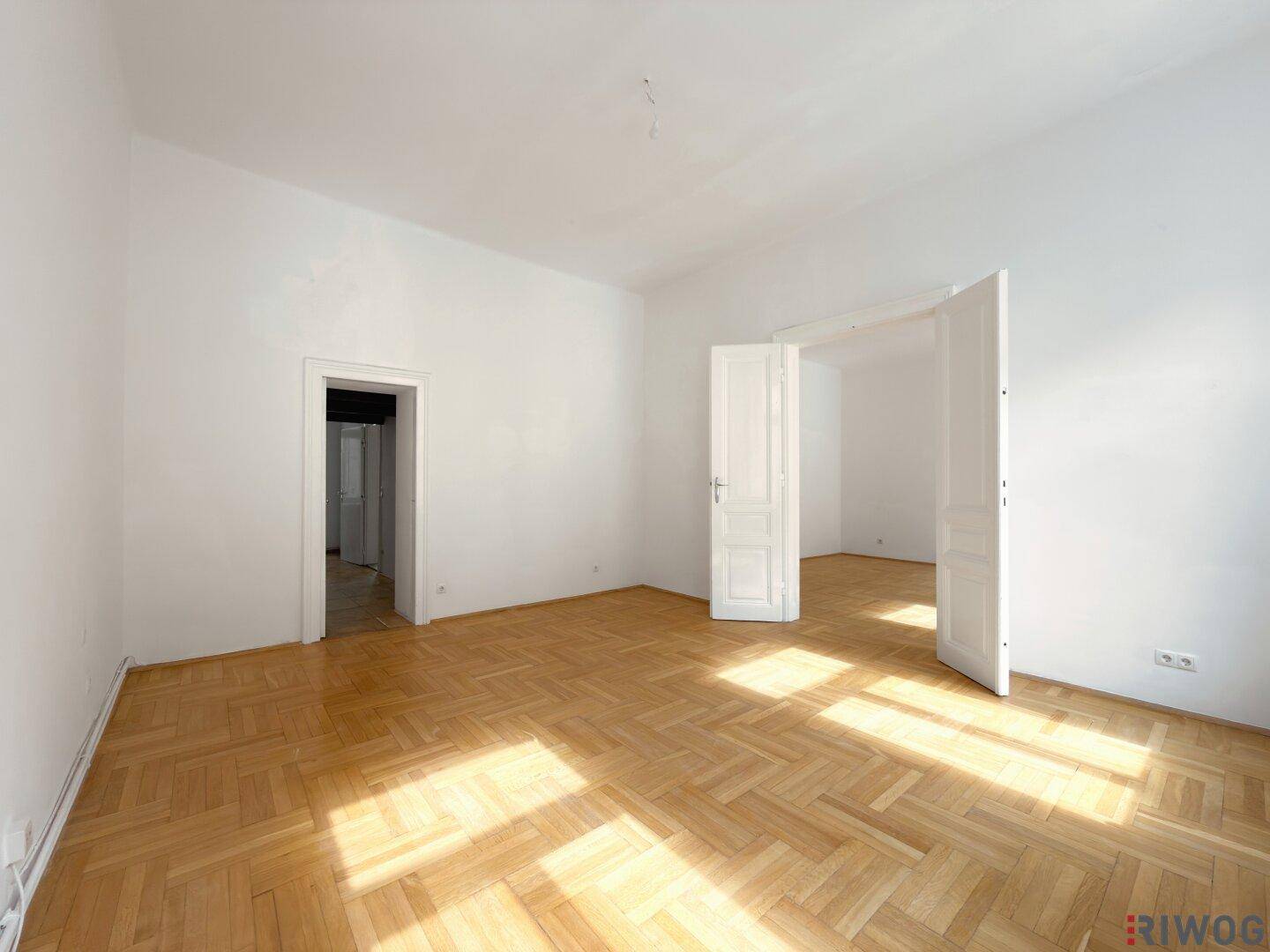 Helles, leeres Zimmer mit Parkettboden und hohen Decken, ideal für individuelle Gestaltung.