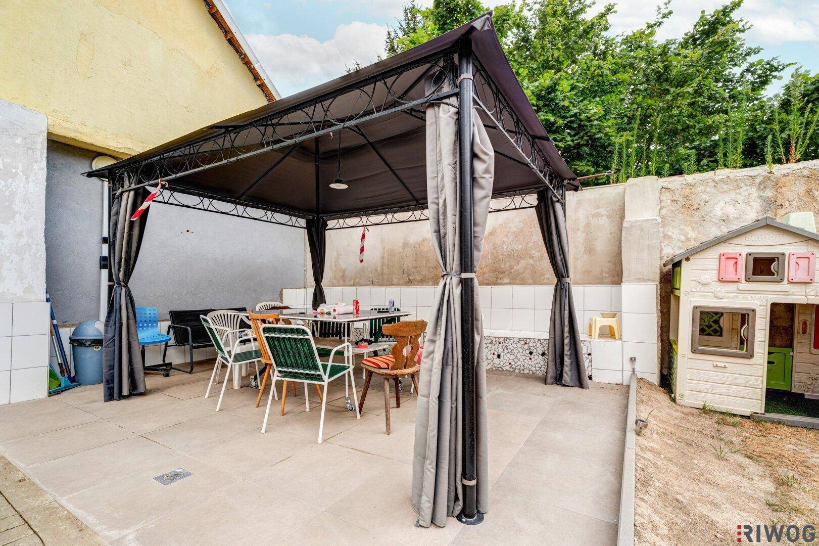 Gemütliche Terrasse mit Pavillon, Esstisch und Stühlen, ideal für Mahlzeiten im Freien und Entspannung.