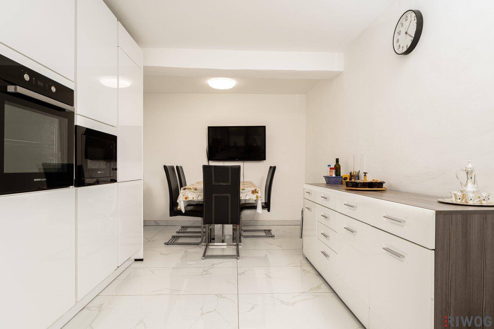 Essbereich in der Küche mit modernem Esstisch, Stühlen und einem Sideboard.