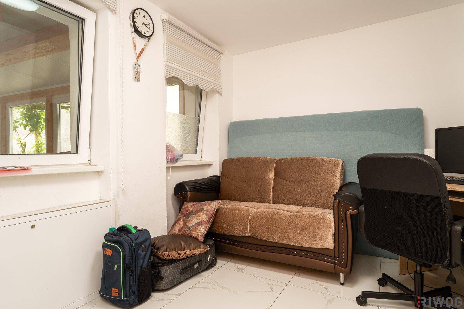 Kleines Büro oder Gästezimmer mit Sofa, Schreibtisch und Fenster für Tageslicht.