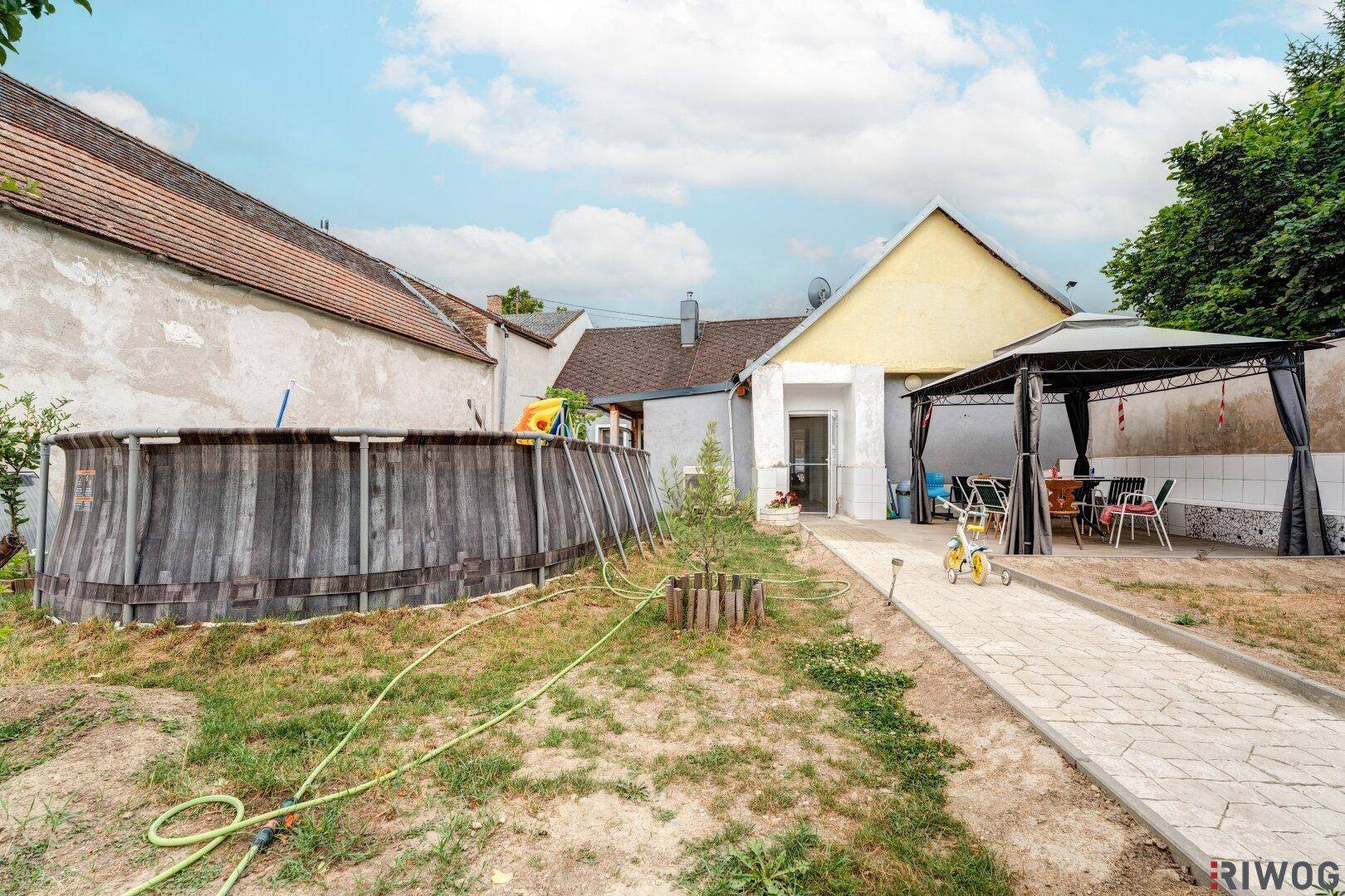 Hinterhof mit Aufstellpool, gepflastertem Weg und einem Pavillon, ideal für sommerliche Aktivitäten.