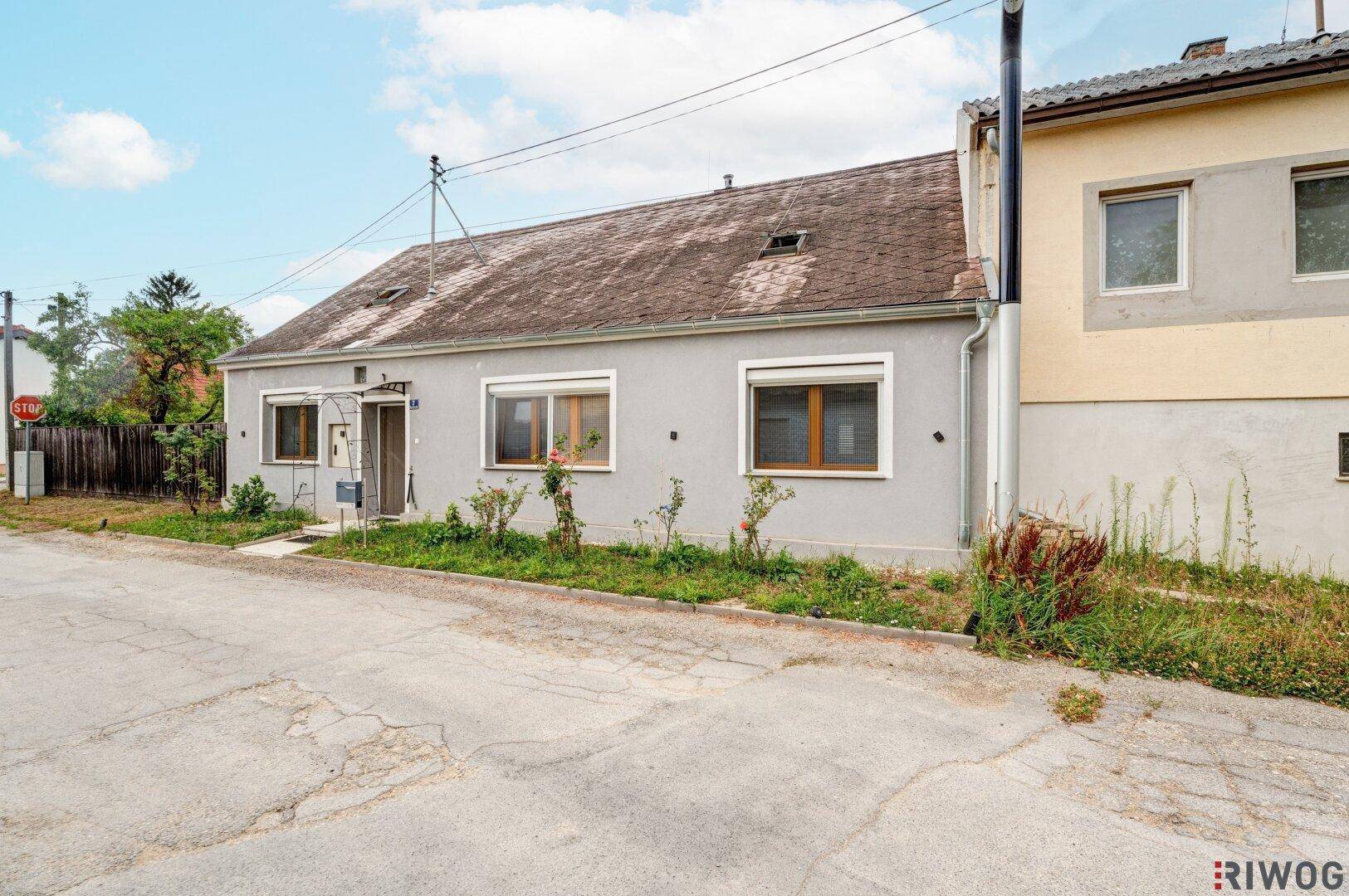 Ansicht des Hauses von der Straße aus, mit einfacher Fassade und Fenstern mit Rollläden.