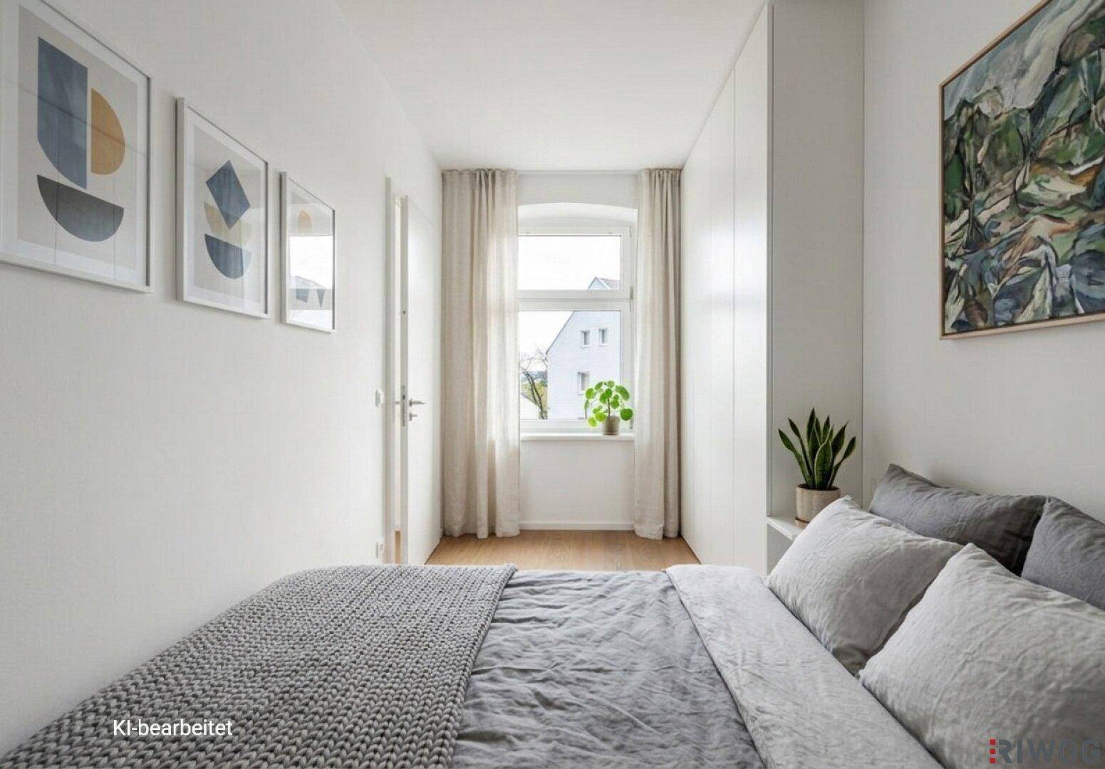 Helles Schlafzimmer mit großem Bett, integrierten Schränken, Holzboden und Fensterblick ins Grüne.