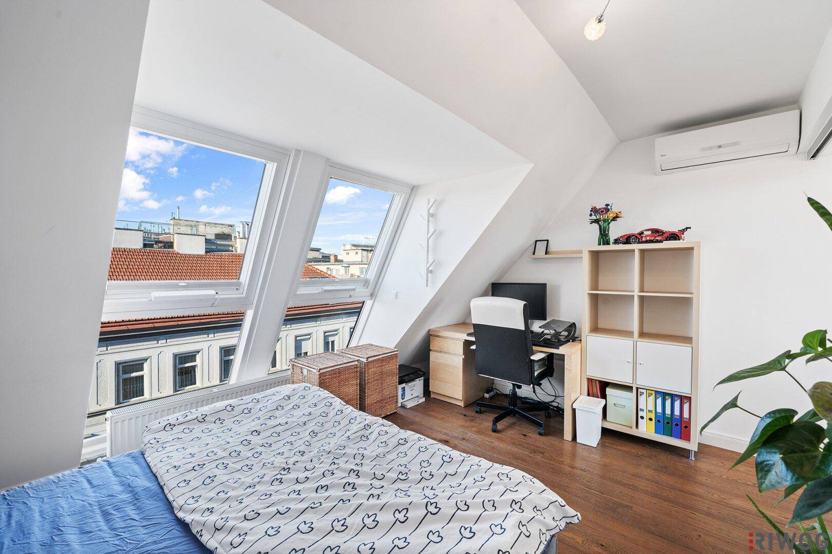 Schlafzimmer mit Arbeitsbereich, Klimaanlage und hellen Dachfenstern.