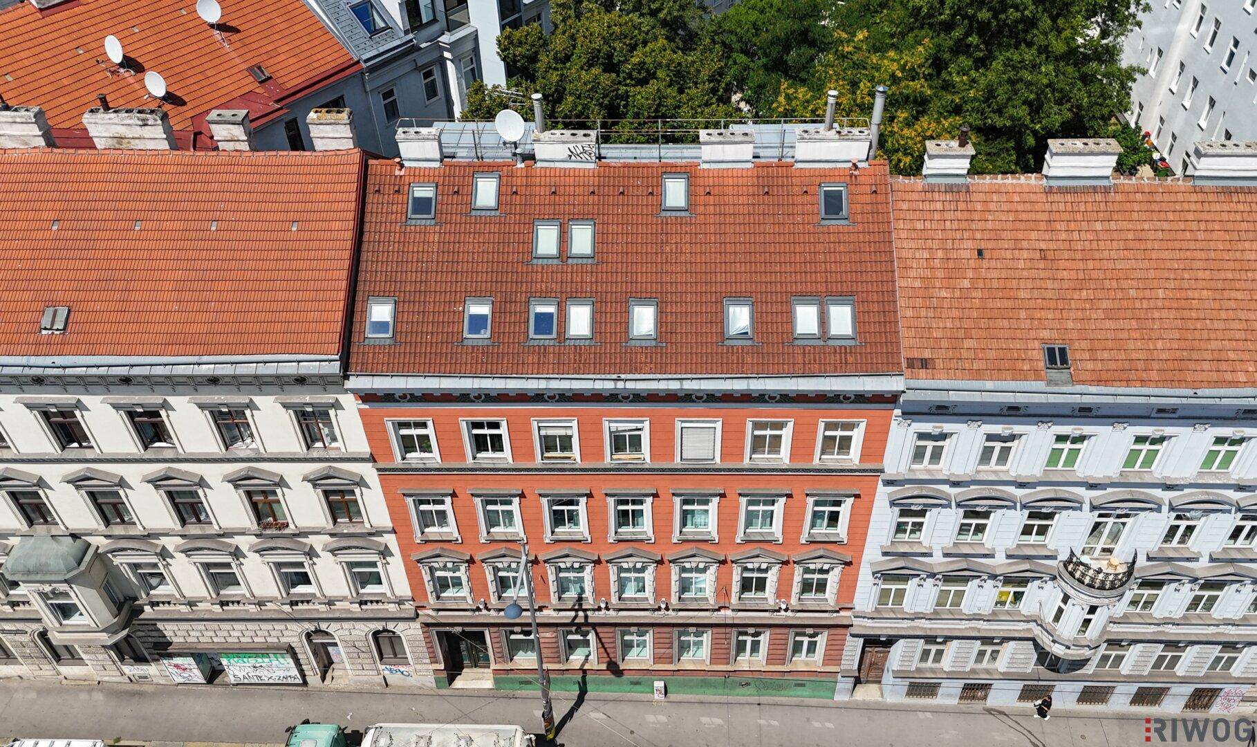 Tagesansicht von Wohngebäuden mit roten Ziegeldächern und zahlreichen Dachfenstern in einer Stadt.