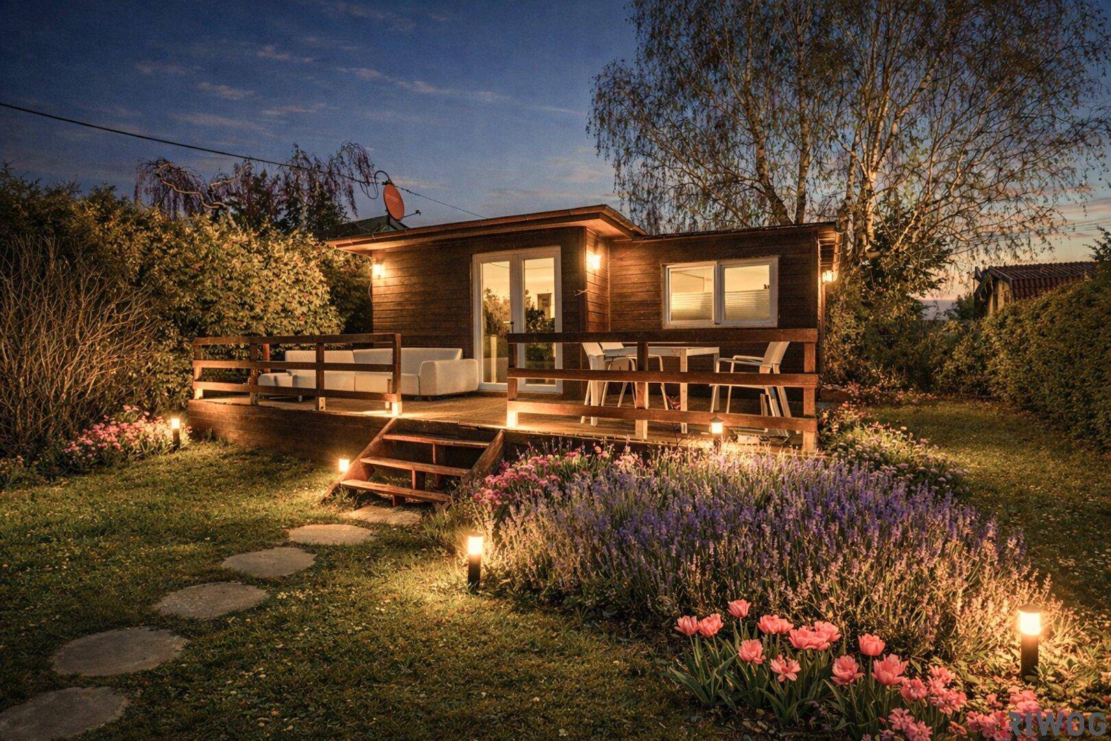 Stimmungsvolle Abendbeleuchtung im Garten und auf der Holzterrasse des Hauses.