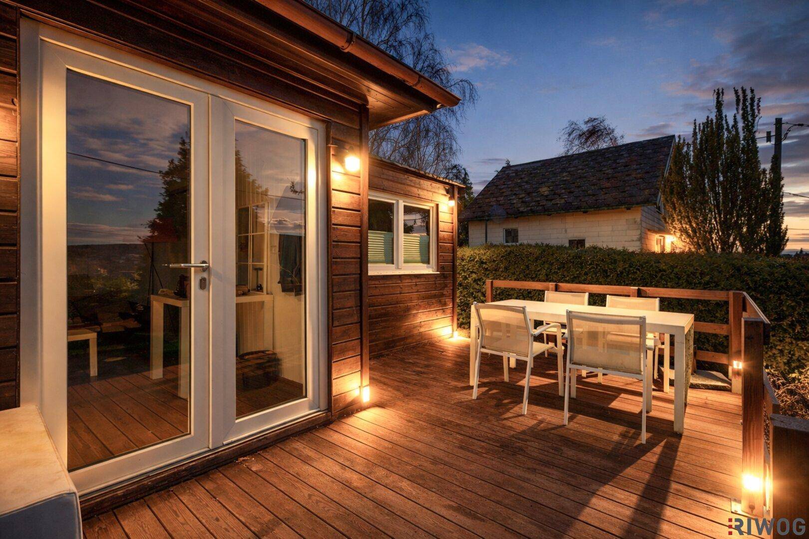 Beleuchtete Holzterrasse mit Zugang zum Haus, ideal für entspannte Abende im Freien.