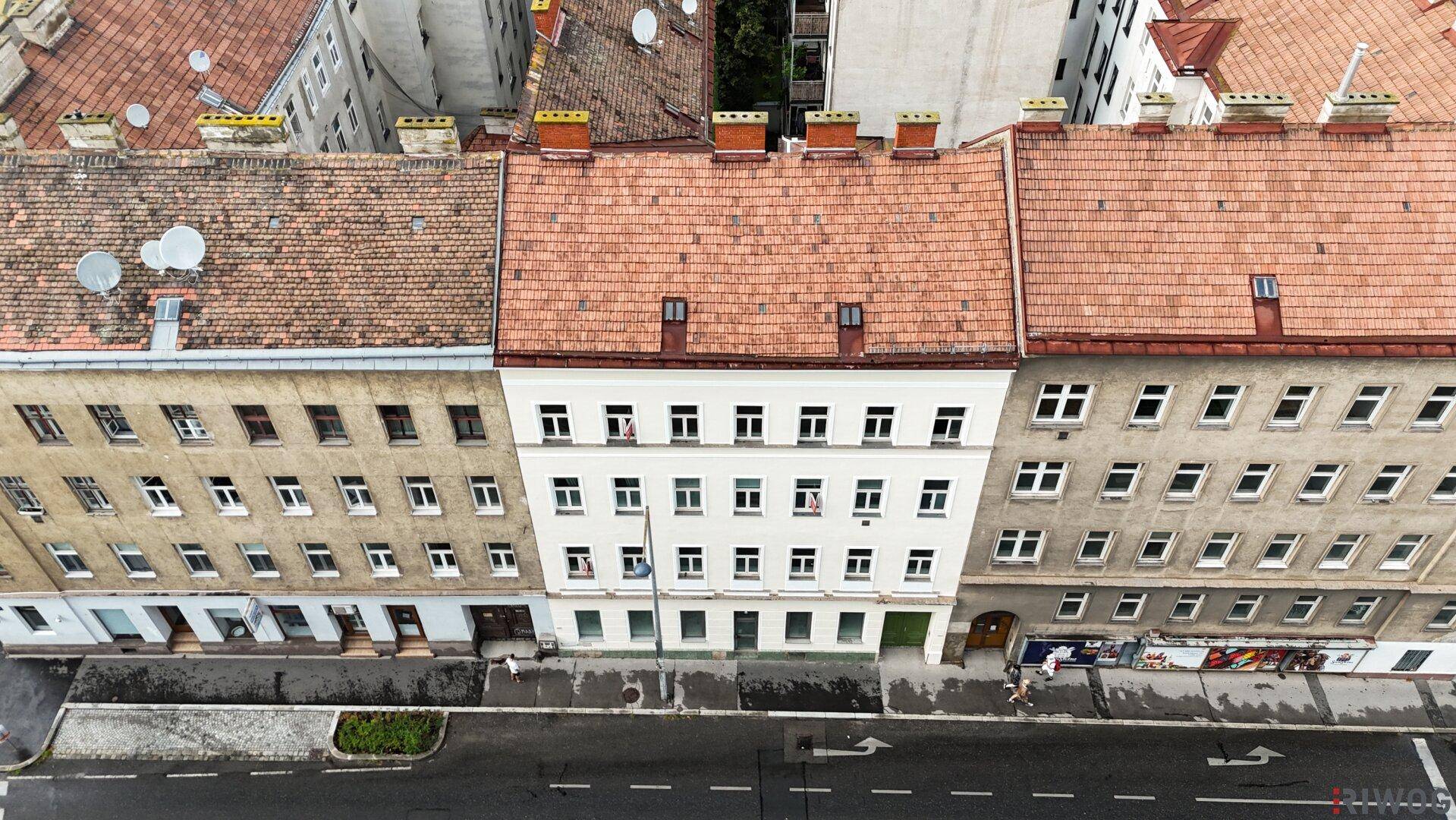 Luftaufnahme von historischen Gebäudefassaden mit Satteldächern und vielen Fenstern in einer städtischen Umgebung.