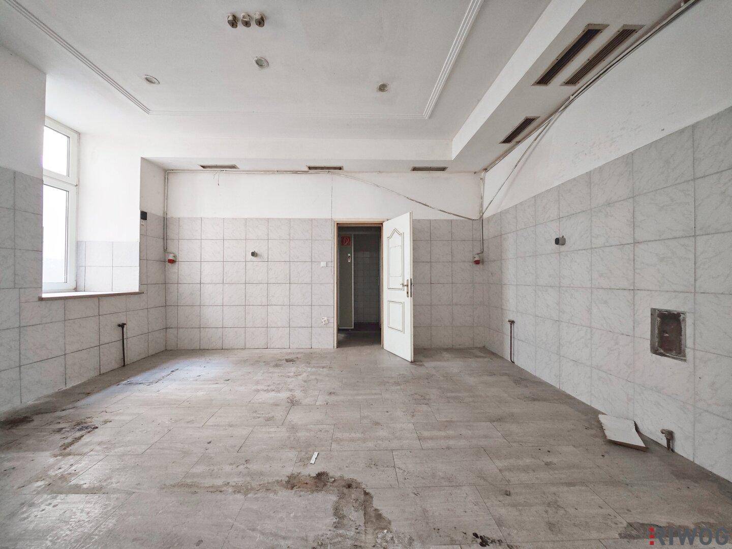 Heller, gefliester Raum mit Fenster und Tür, ideal für gewerbliche Zwecke nach einer Modernisierung.