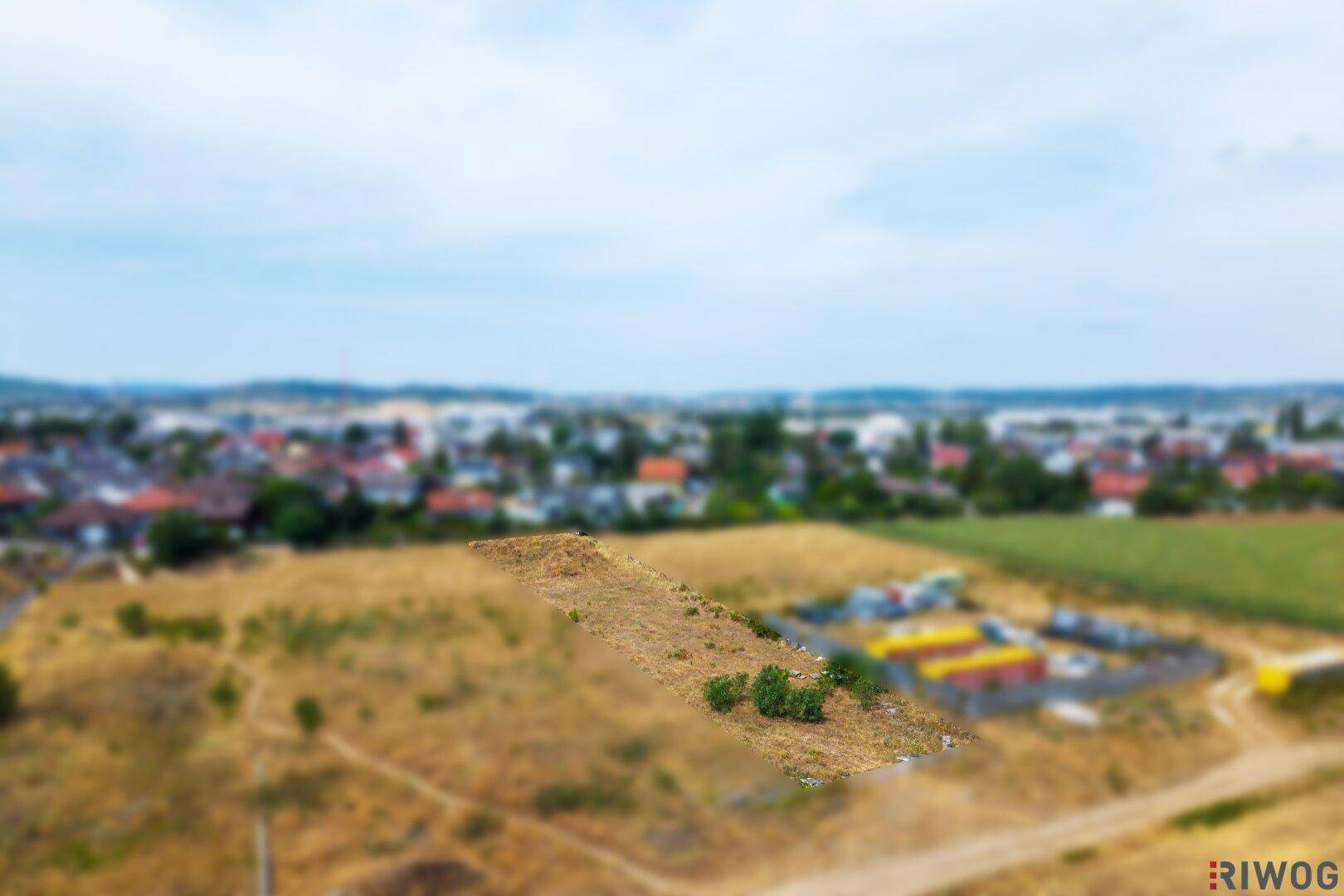 Luftaufnahme eines unbebauten Grundstücks mit trockener Erde und Gras, umgeben von einer ländlichen Umgebung.