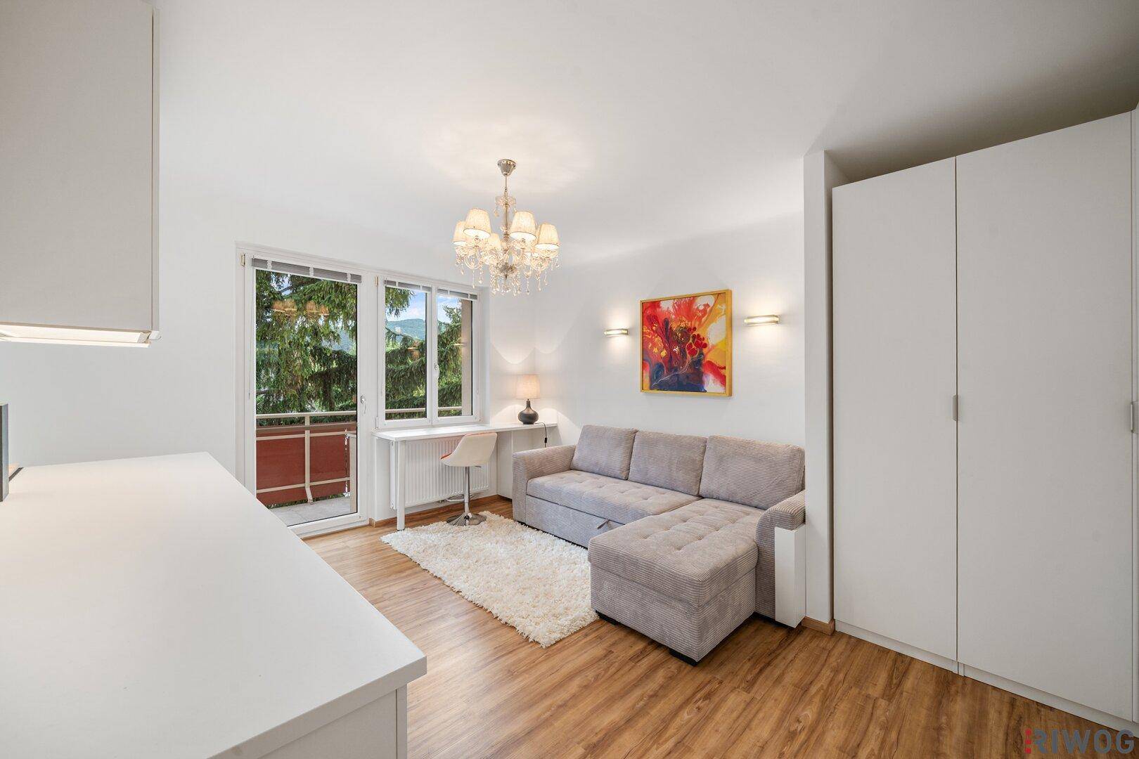 Gemütlicher Wohnbereich mit Sofa, Spiegelschrank und Zugang zu einem kleinen Balkon.