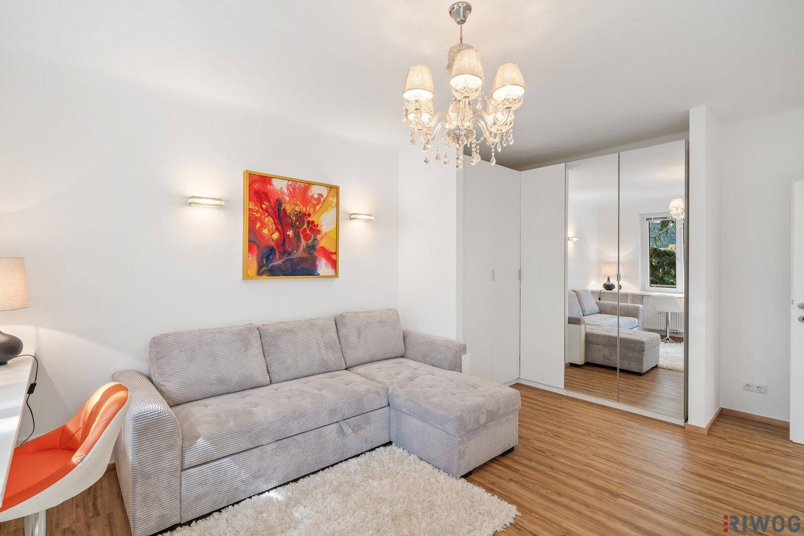 Heller Wohnraum mit beigem Sofa, Spiegelschrank und dekorativer Wandbeleuchtung.