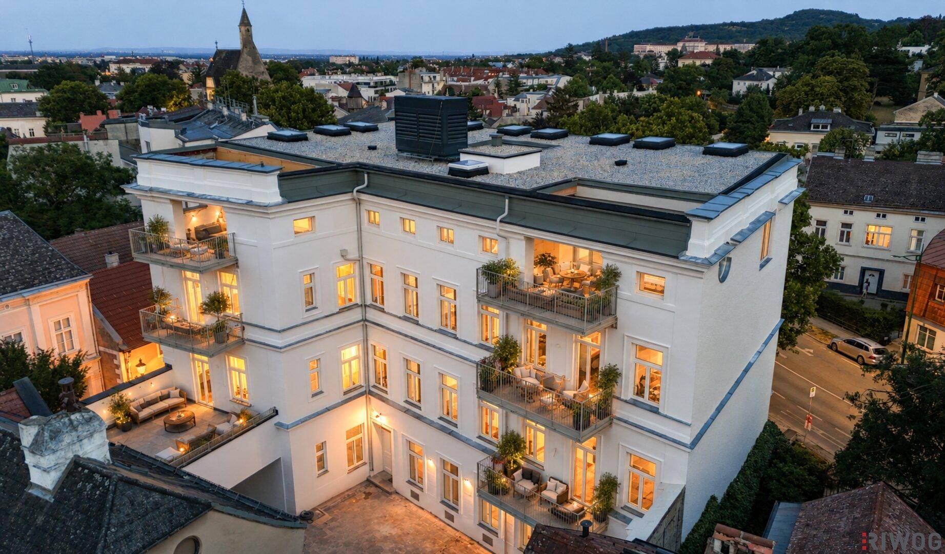 Gebäudeansicht mit mehreren möblierten Balkonen und einer großzügigen Terrasse im Erdgeschoss.