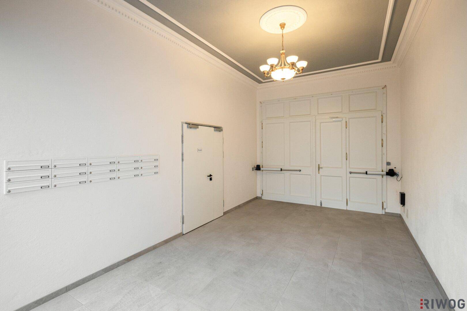 Geräumiger Eingangsbereich mit Briefkästen, einer Tür und einer eleganten Deckenleuchte.