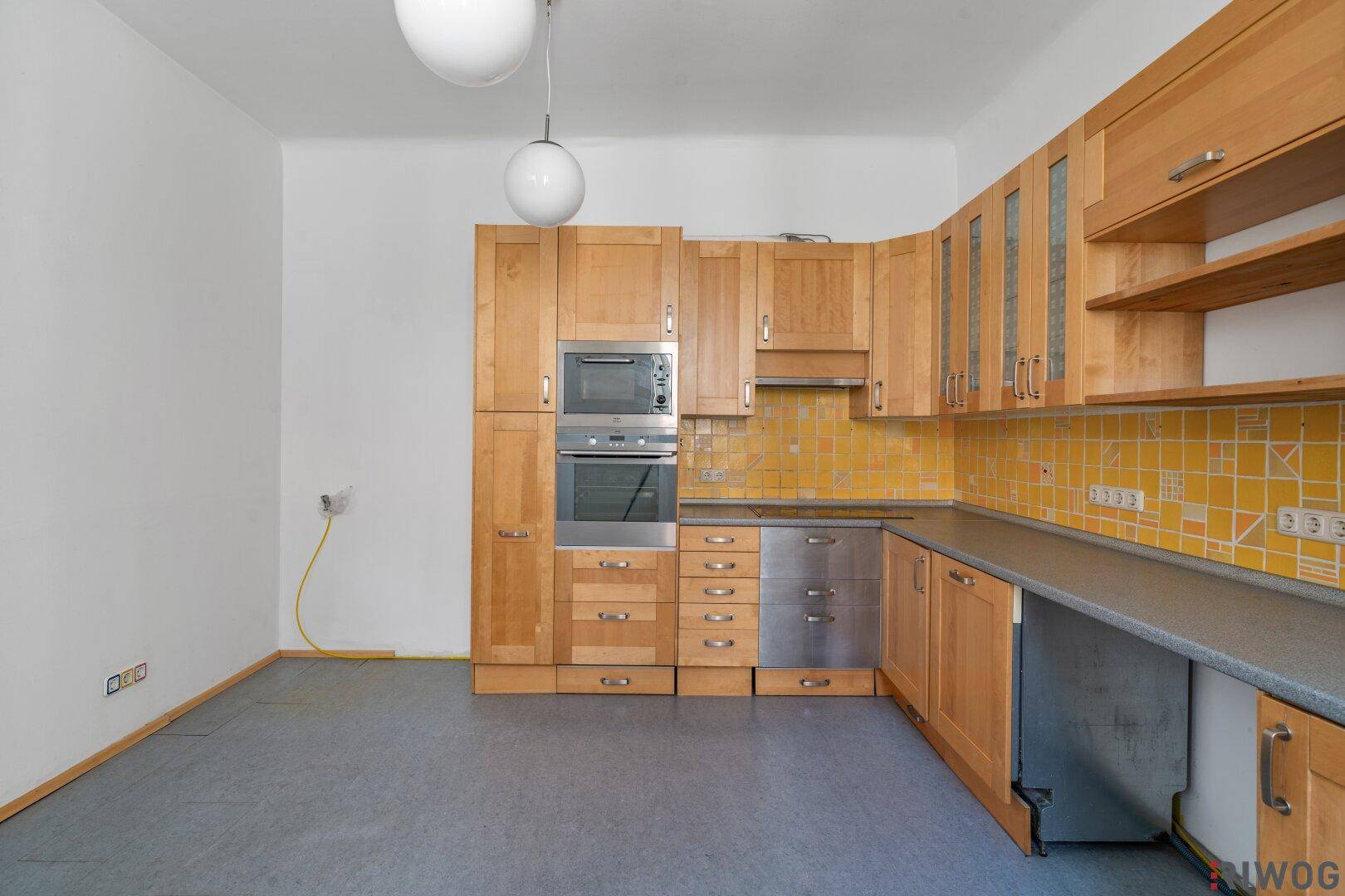 Geräumige Küche mit Holzschränken, gelben Fliesen und integrierten Elektrogeräten.