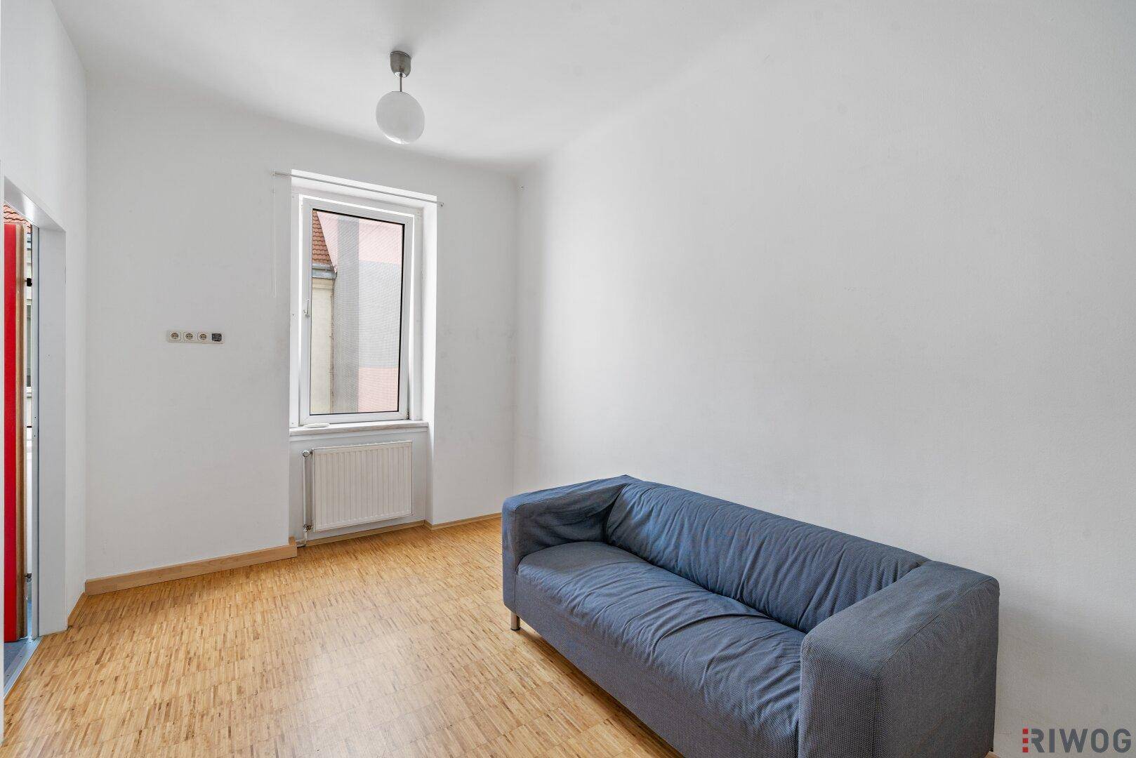 Gemütliches Wohnzimmer mit Holzboden und einem blauen Sofa, ideal zum Entspannen.
