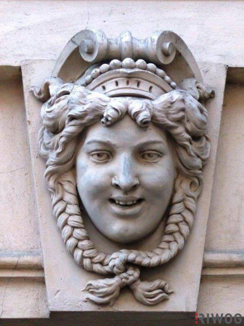 Nahaufnahme einer weiteren detaillierten steinernen Maskaron-Skulptur an der historischen Fassade.