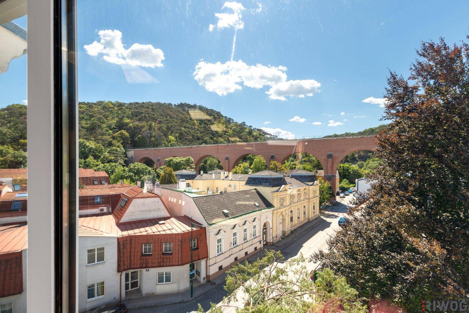 Weitblick aus einem Fenster auf ein historisches Viadukt und die umliegende Stadtlandschaft.